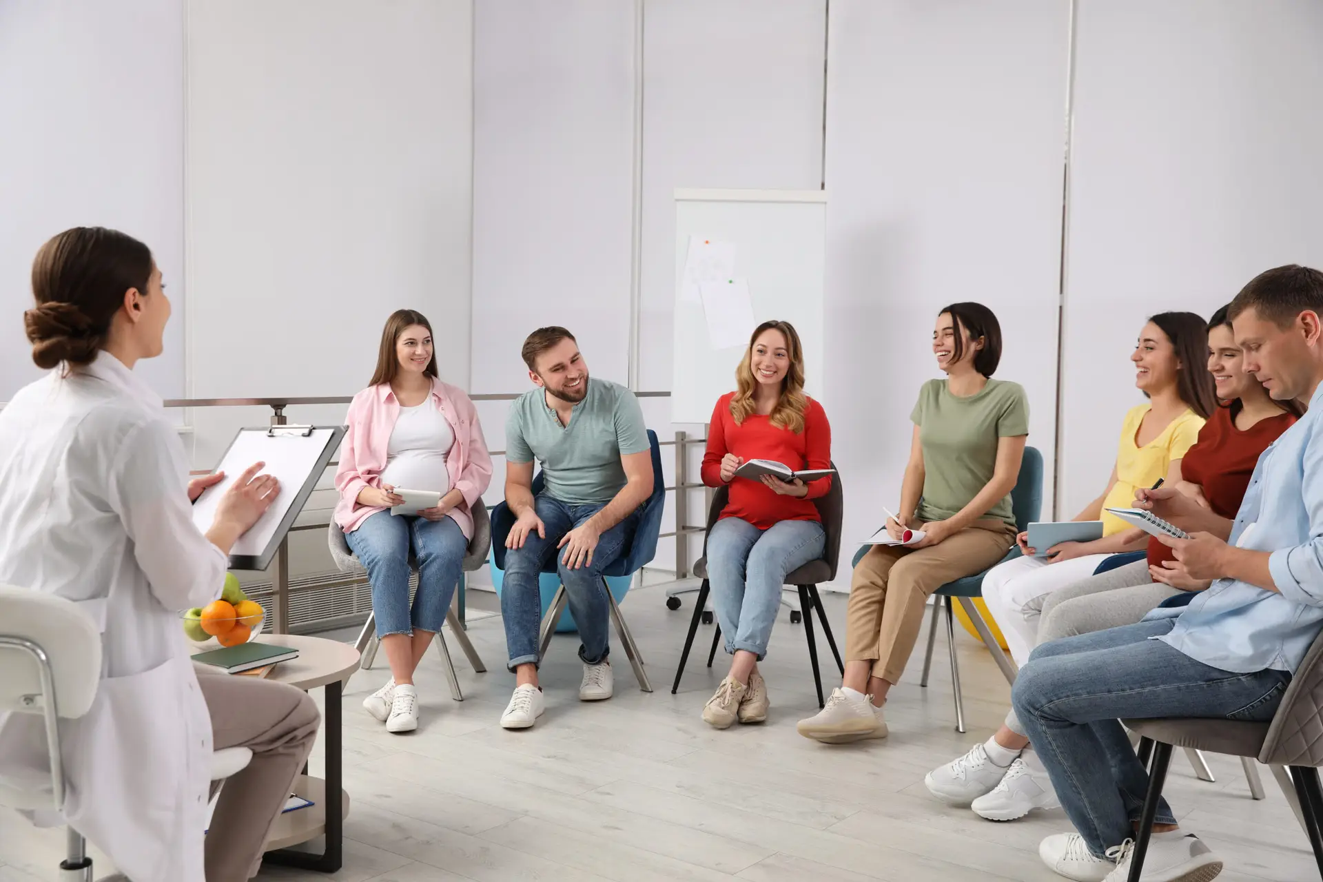 Group of pregnant women with men and doctor at courses for expec