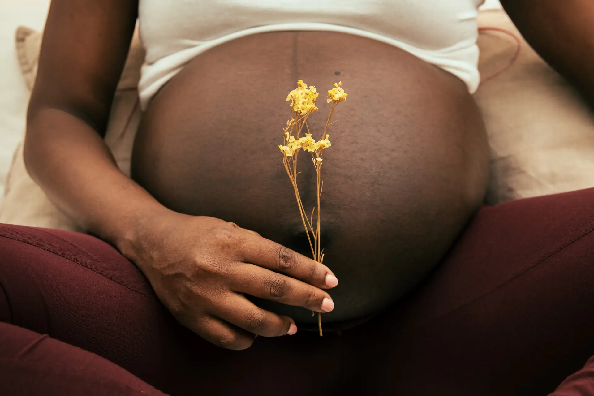 Pregnant woman holding a flower in front of his belly